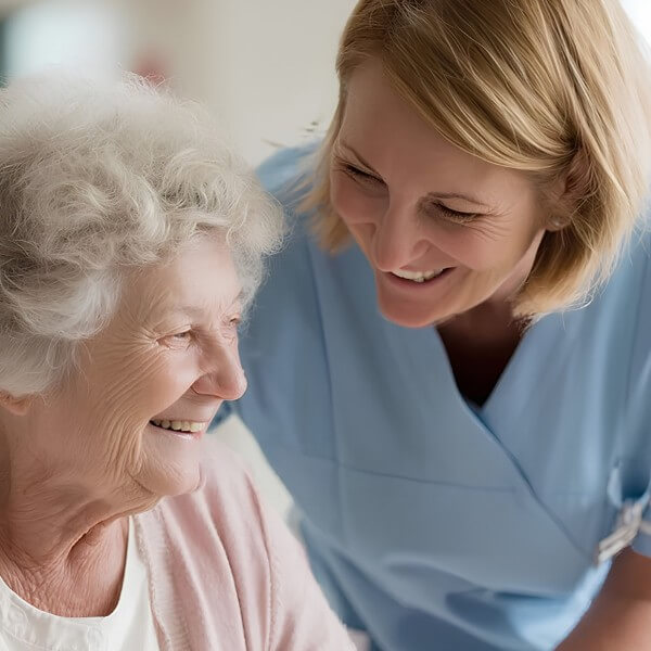 Care worker smiling with an older woman during a supportive conversation