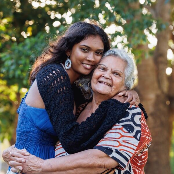 Young woman embracing an older woman outdoors