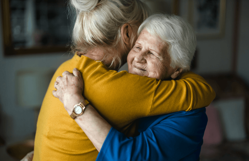 Older woman in an embrace with a younger women in relation to having respectful end of life conversations.