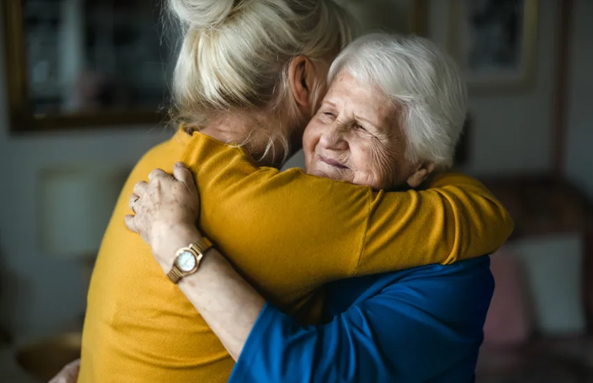 Older woman in an embrace with a younger women in relation to having respectful end of life conversations.