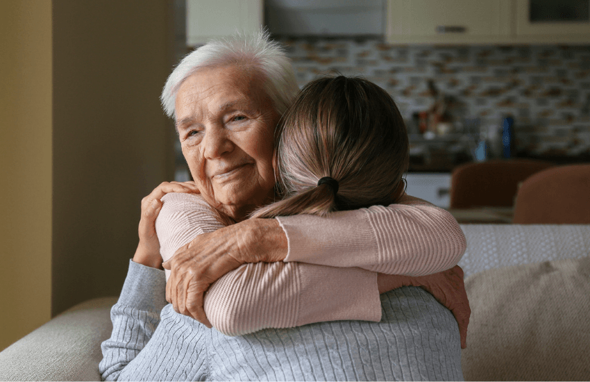 An older lady hugging a younger lady.