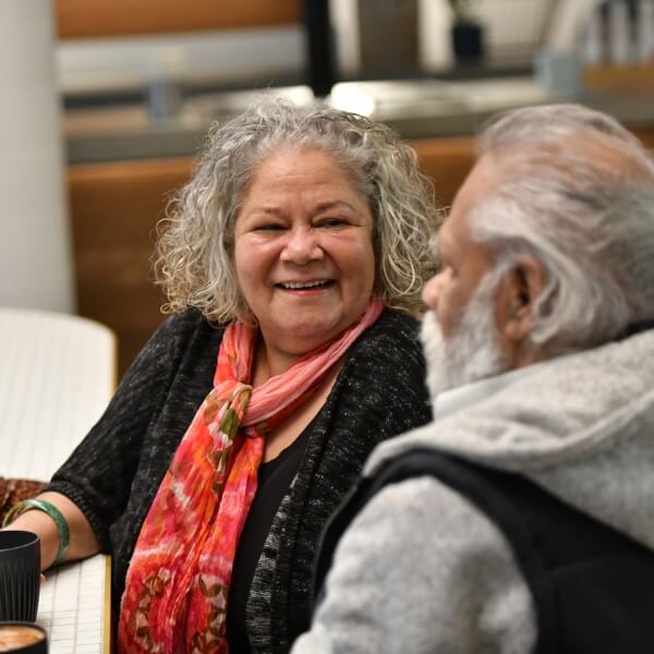 Older woman smiling while talking with an older man at a table