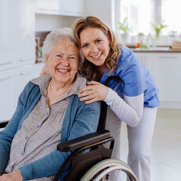 Older woman in a wheelchair with a smiling in-home care nurse