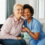 Older woman in a wheelchair embracing her in-home nursing nurse