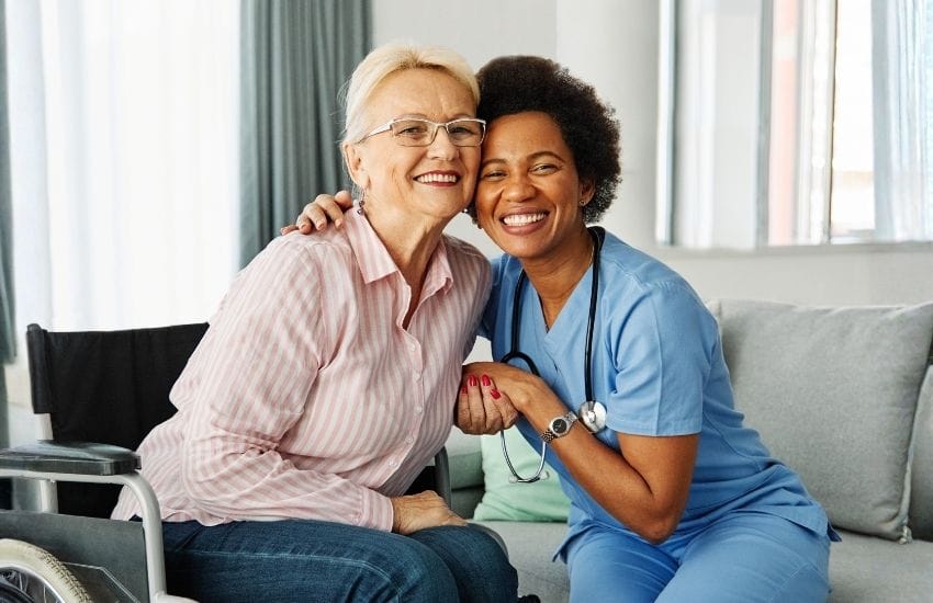Older woman in a wheelchair embracing her in-home nursing nurse
